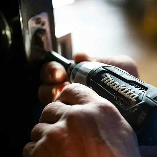 Handyman using power drill to install or repair a door lock